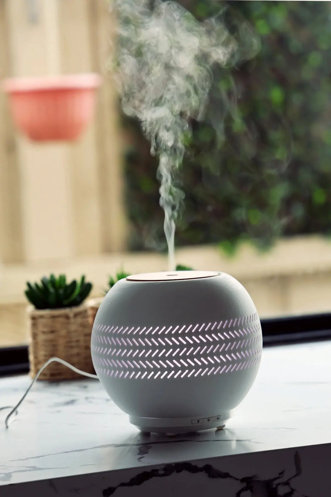 A humidifier sitting on top of a counter next to a potted plant